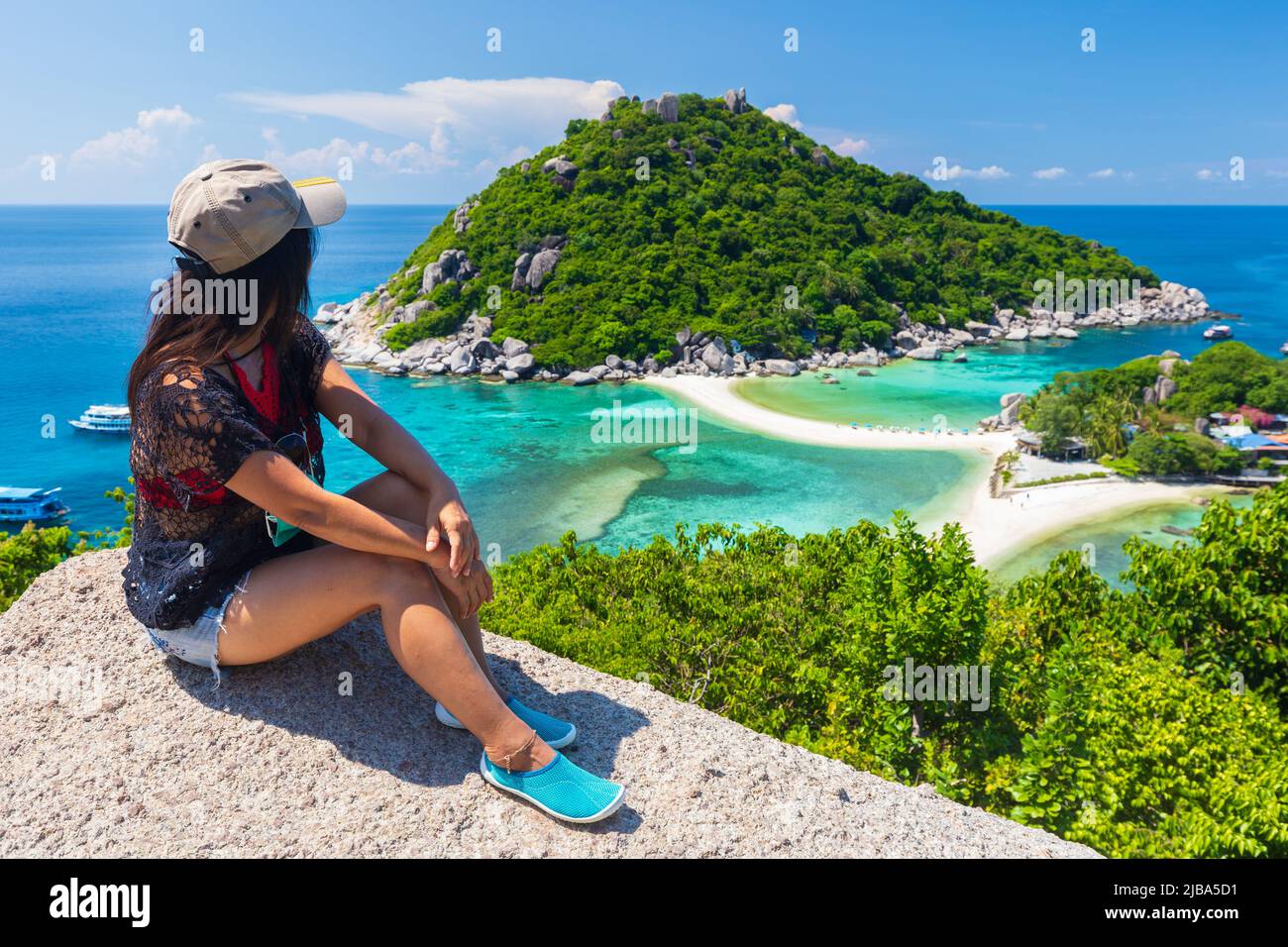 Donna asiatica seduta su una roccia in cima guardando il paesaggio idilliaco dell'isola di Koh Nang Yuan in Thailandia Foto Stock