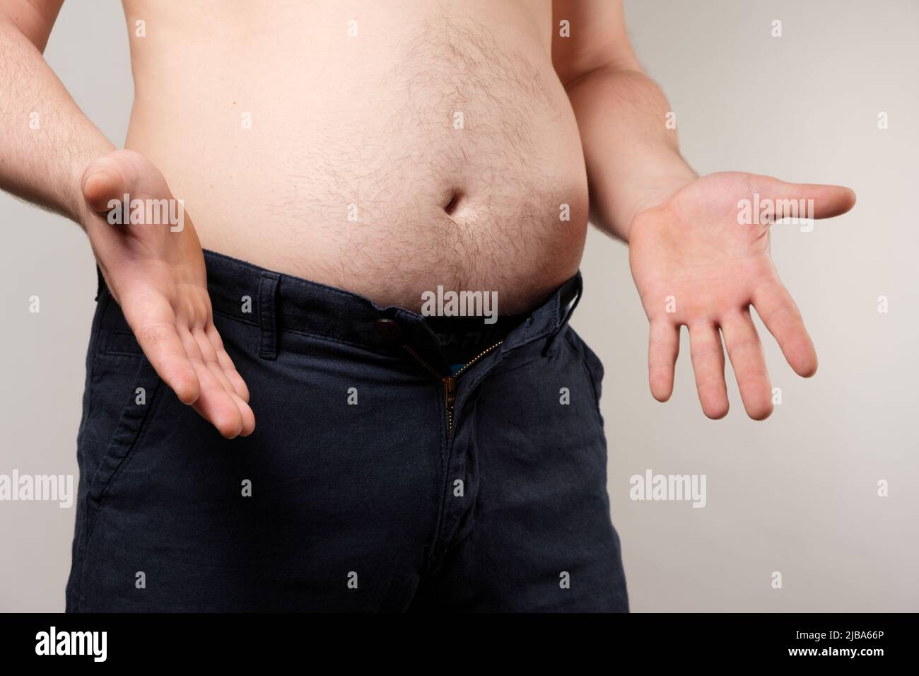 Un uomo in pantalone stende le braccia ai lati. Il concetto di obesità maschile. Foto Stock