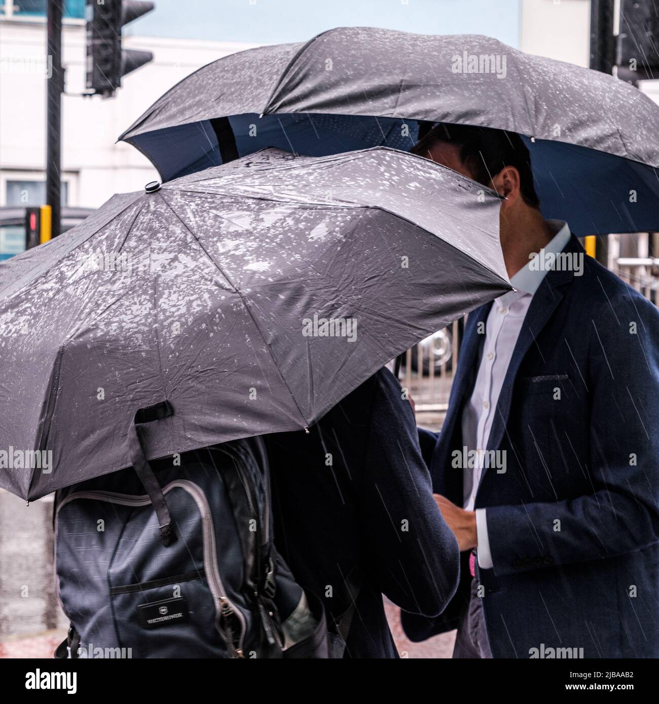 Epsom Surrey, Londra UK, giugno 04 2022, gli uomini che riparano sotto gli ombrelloni in Un giorno piovoso bagnato Foto Stock