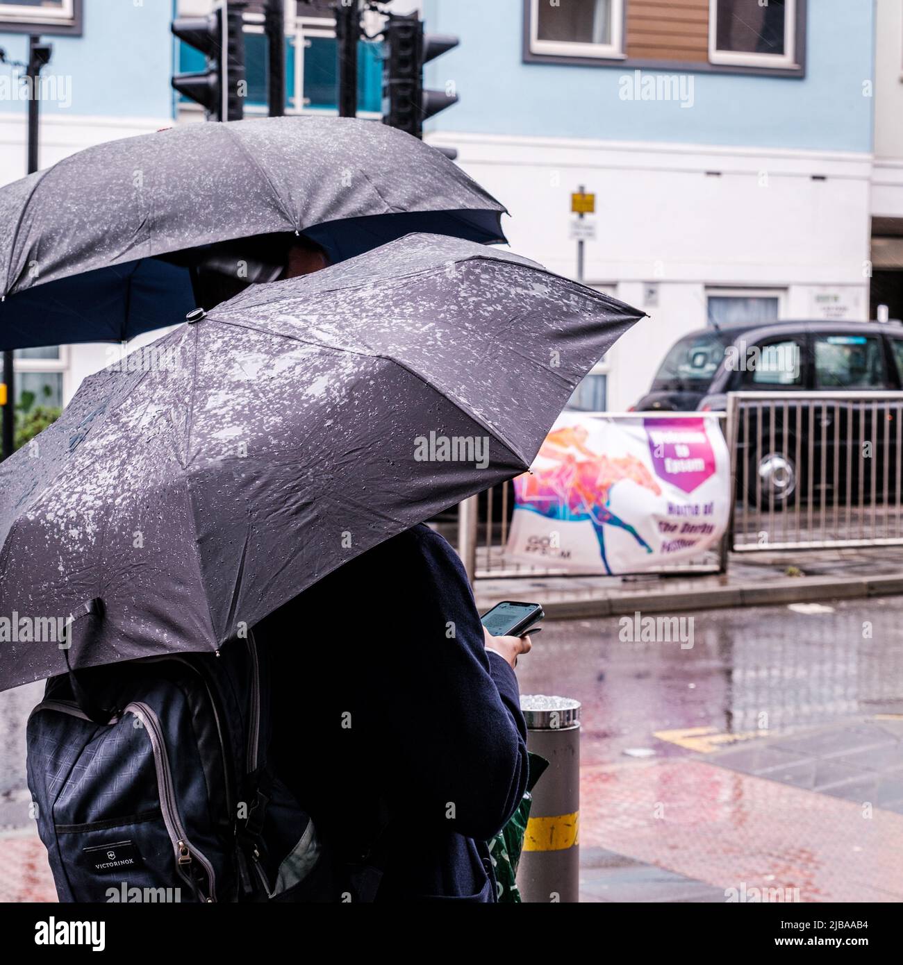 Epsom Surrey, Londra UK, giugno 04 2022, gli uomini che riparano sotto gli ombrelloni in Un giorno piovoso bagnato Foto Stock