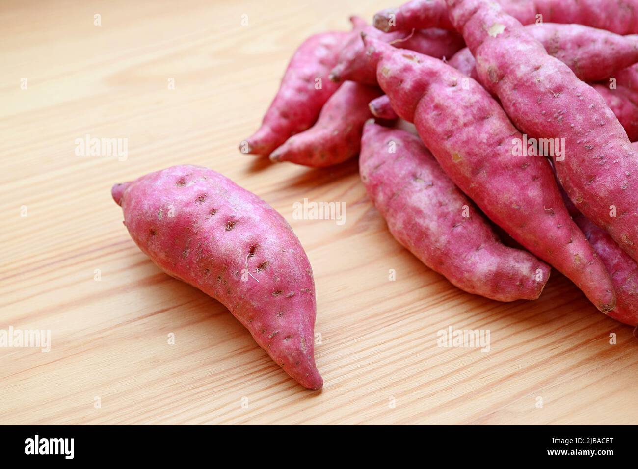 Primo piano di patate dolci crude viola su sfondo di legno Foto Stock