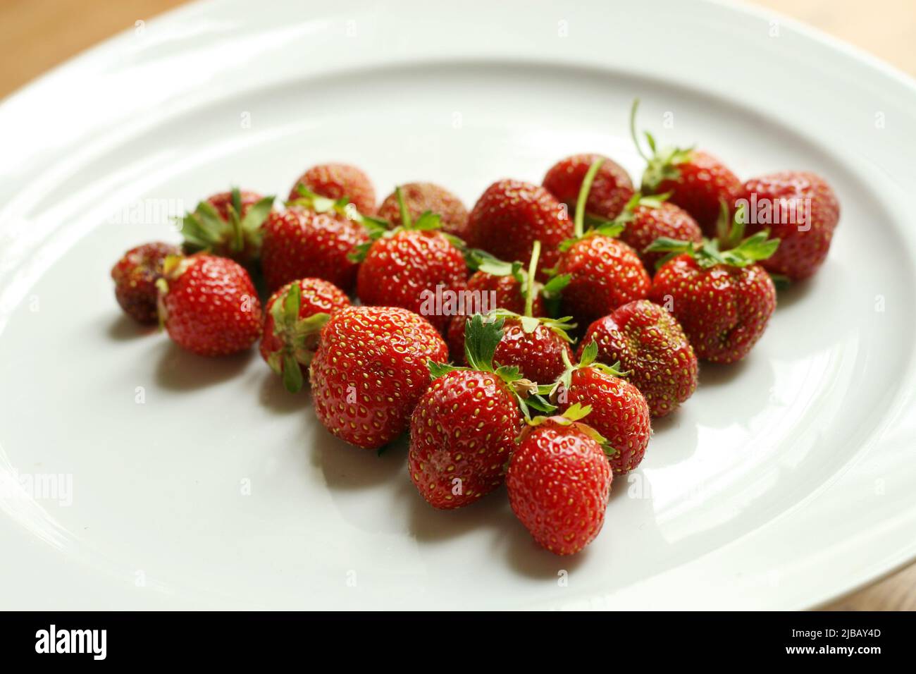 Fragole fresche sul piatto bianco disposte a forma di cuore. San Valentino. Romanticismo. Amore Foto Stock