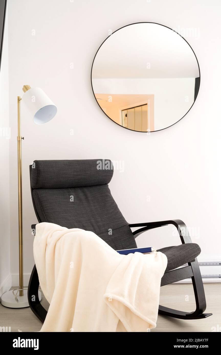 Una poltrona con una coperta e prenotare in un report Air BnB hotel unità. Foto Stock