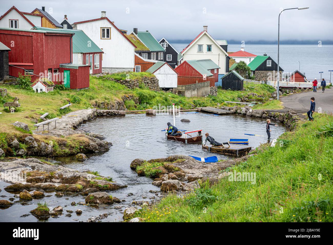 Bambini che giocano su un laghetto artificiale nel villaggio di Gjogv, Isola Eysturoy, Arcipelago di Faroe Foto Stock