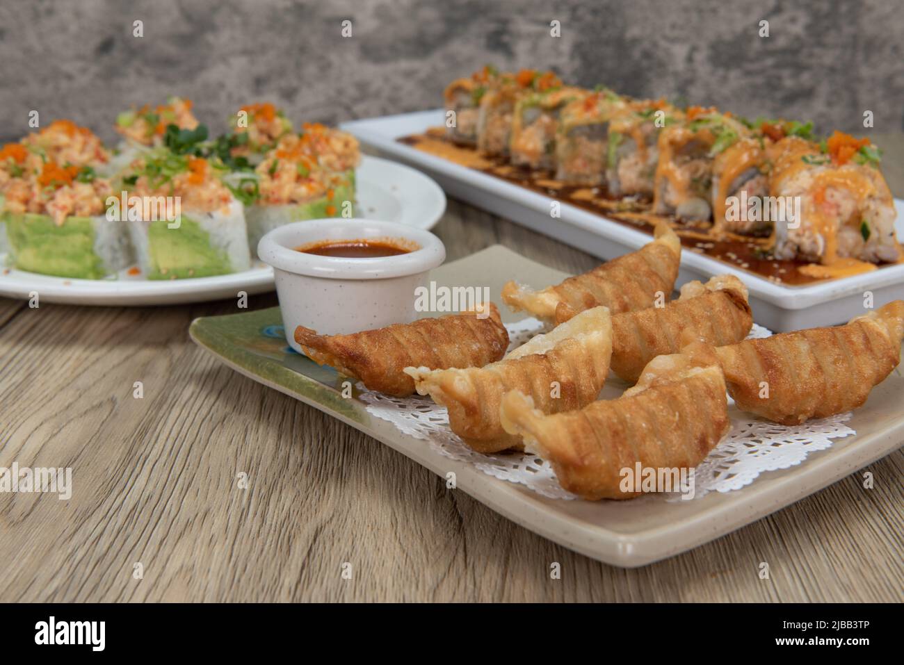 La cucina asiatica si festeggia al tavolo con una scelta di sushi roll o gyoza fritta da mangiare. Foto Stock