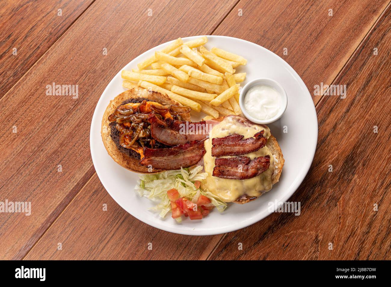 Primo piano con hamburger freschi su un tavolo di legno con patatine fritte. Deliziosi cheeseburger. Hamburger fatto in casa con manzo, pancetta e formaggio. Foto Stock