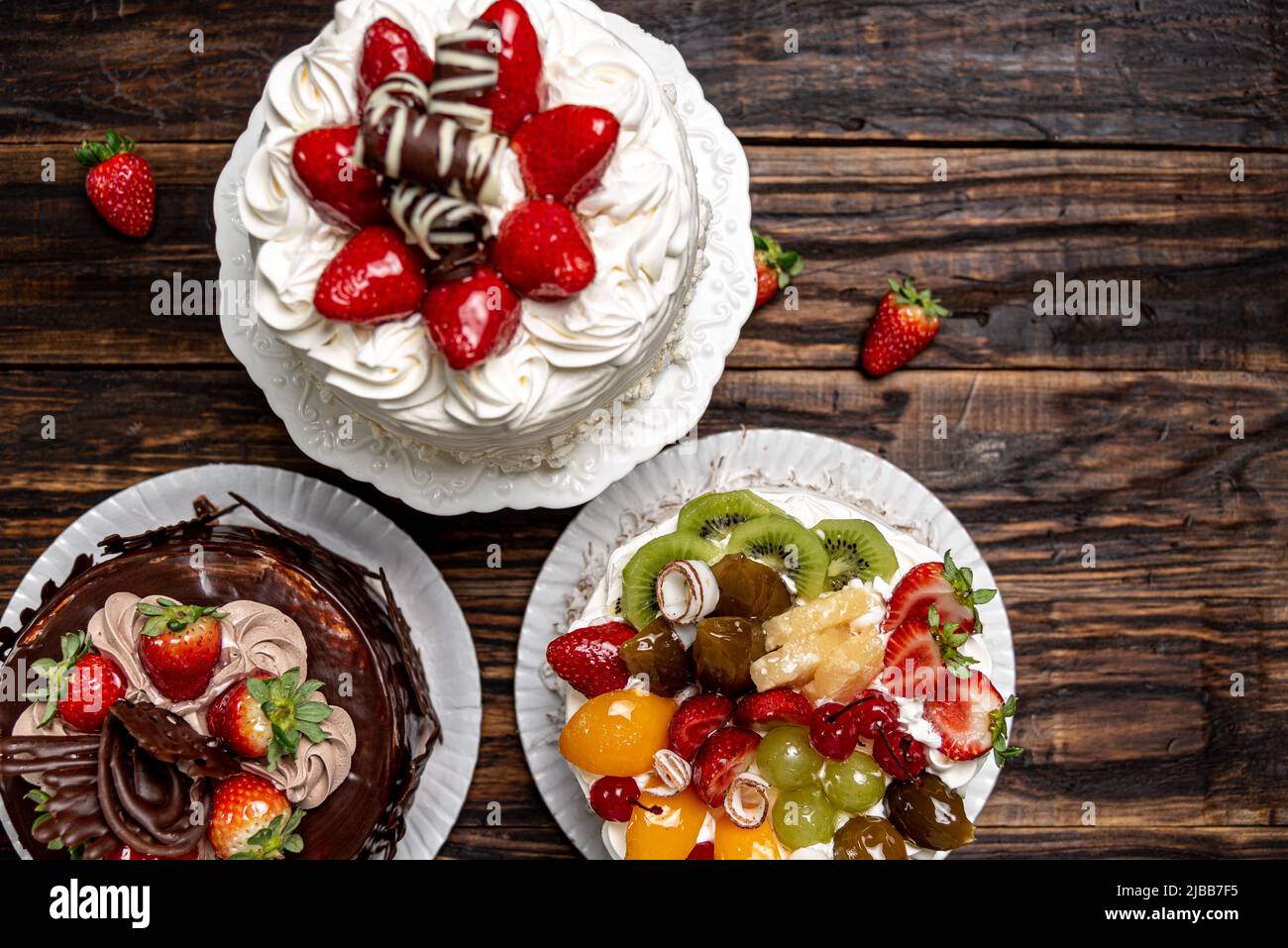 Torte varie su sfondo o tavolo di legno. Assortimento di torte per feste. Foto Stock