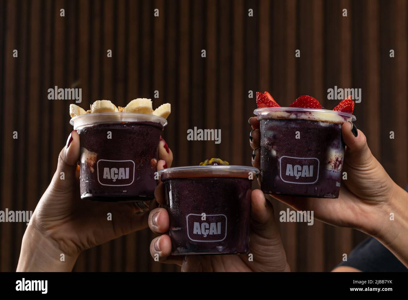 Mix di deliziosa Açaí crema brasiliana, in una tazza di plastica con una varietà di condimenti. Frullato estivo di acai Foto Stock