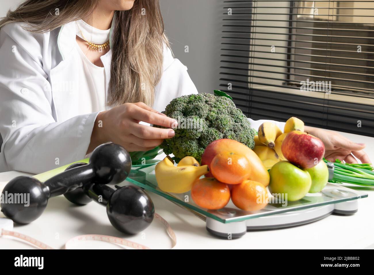 Nutrizionista femminile nel suo ufficio, mostrando verdure e frutta sane. Concetto di salute e dieta. Stile di vita. Foto Stock