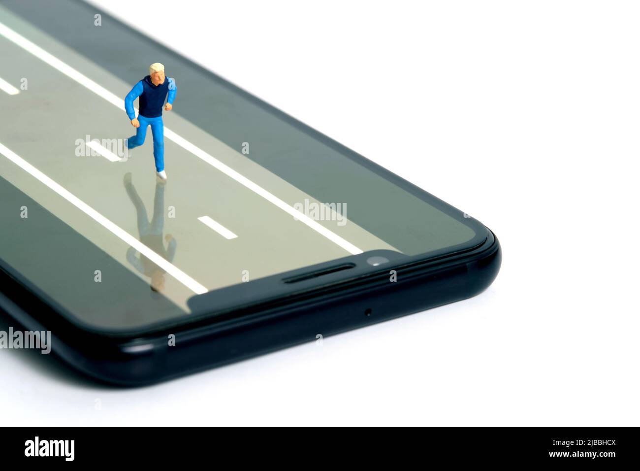 Concetto di app per il monitoraggio della corsa e del jogging. Un uomo che corre sopra lo smartphone. Fotografia di figure di persone in miniatura. Foto Stock