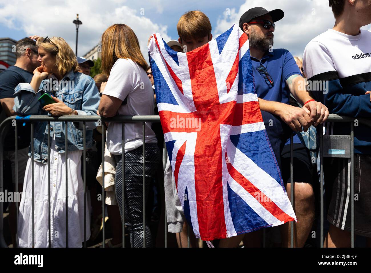 Londra, Regno Unito. 2nd giugno 2022. Un ragazzo drappeggia una grande bandiera di Union Jack su una barriera mentre le folle si riuniscono per Trooping the Color in Trafalgar Square durante la celebrazione. I Royal Well Wishers si riuniscono a Trafalgar Square per celebrare Trooping the Color come parte del Queen's Platinum Jubilee di Londra. (Credit Image: © Tejas Sandhu/SOPA Images via ZUMA Press Wire) Foto Stock