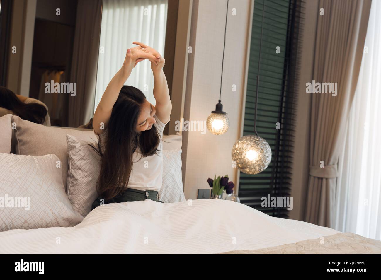 Donna asiatica che si allunga mentre si sveglia al mattino. Foto Stock