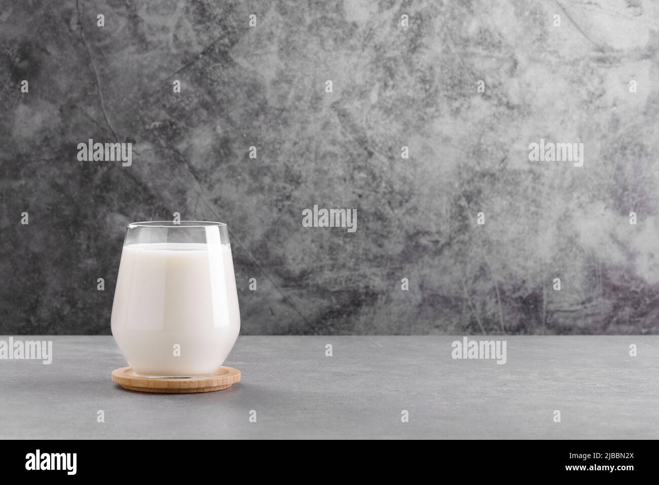 Latte in un vetro su tavola di pietra grigia sfondo minimo con spazio di copia. Latte privo di lattosio fatto di ingredienti vegani. Fonte di calcio Foto Stock