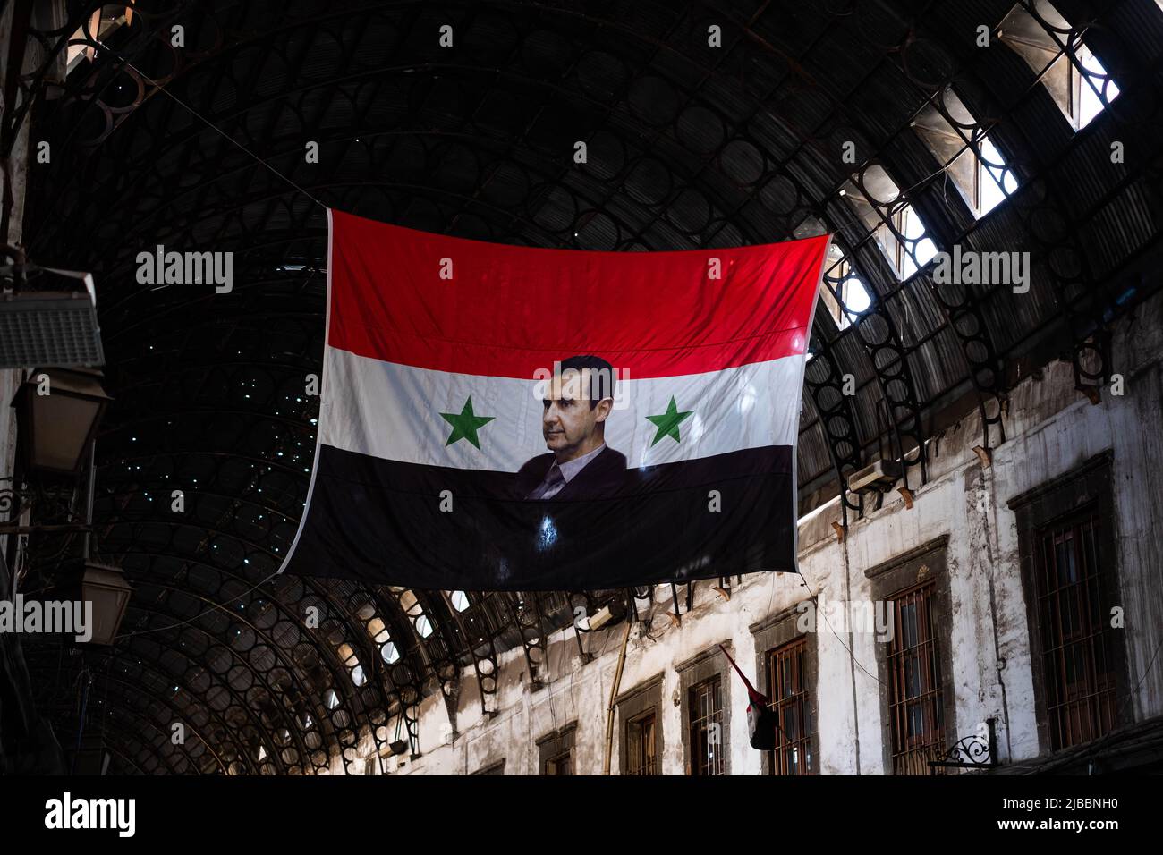 Damasco, Siria - Maggio, 2022: Ritratto di Bashar al-Assad, presidente della Siria sulla bandiera siriana a Suq Foto Stock
