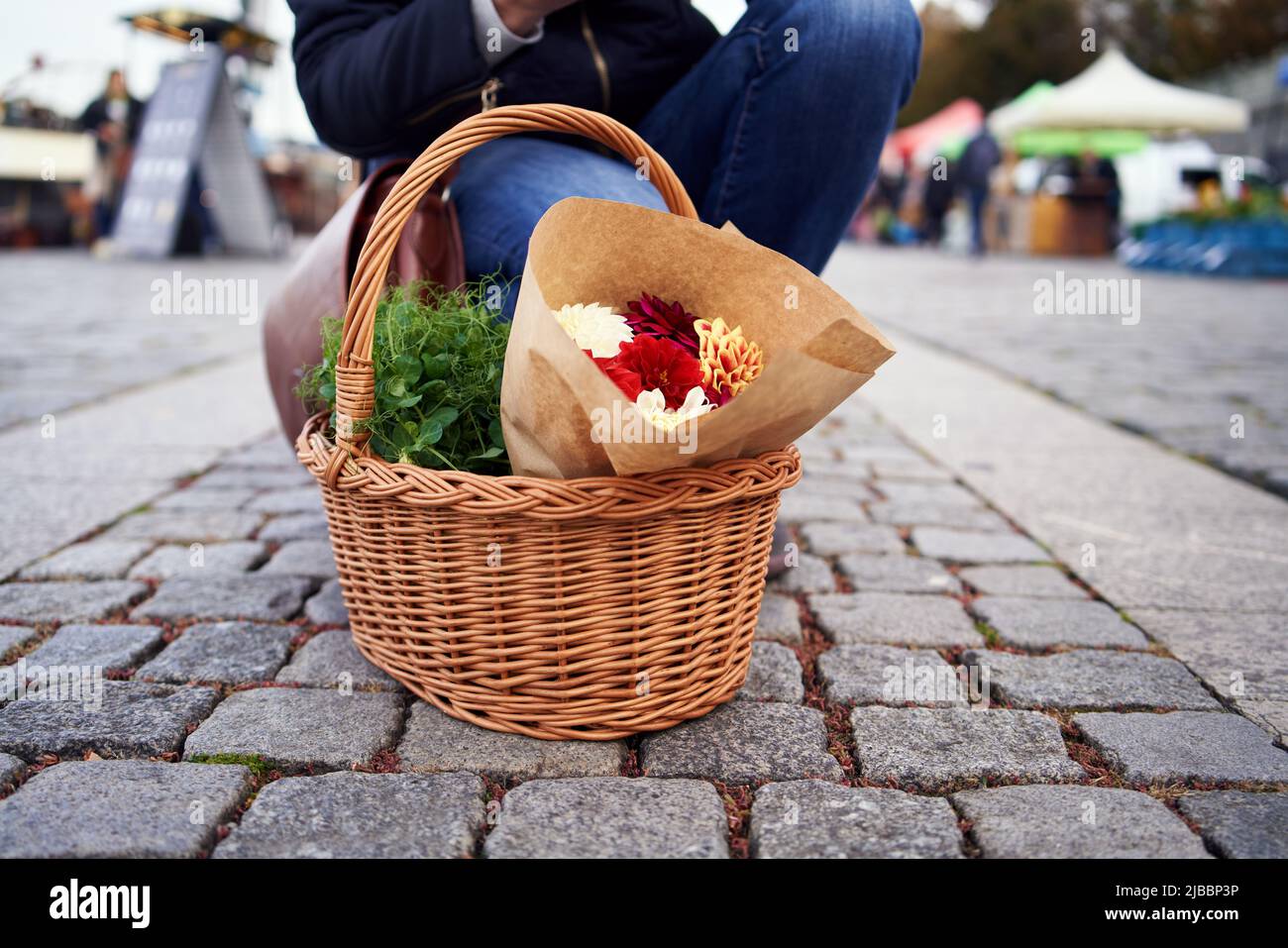 Cestino con microgreens freschi di piselli e fiori al mercato agricolo, con una persona sullo sfondo Foto Stock Cestino con microgreens freschi di piselli e fiori al mercato agricolo, con una persona sullo sfondo Foto Stock