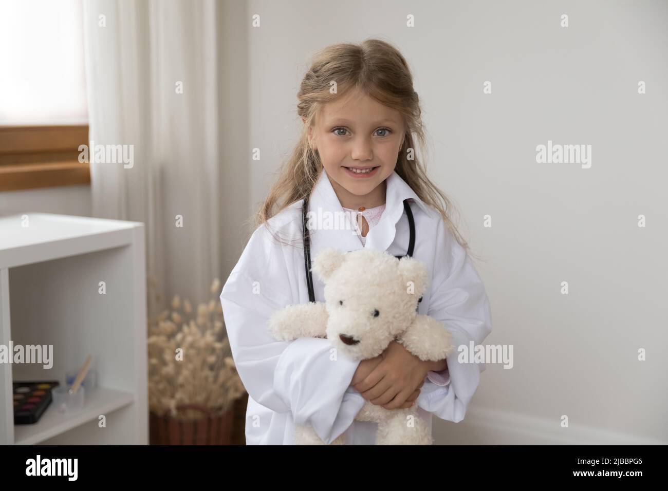 Bambina in uniforme tenendo l'orso giocattolo guardare la macchina fotografica Foto Stock