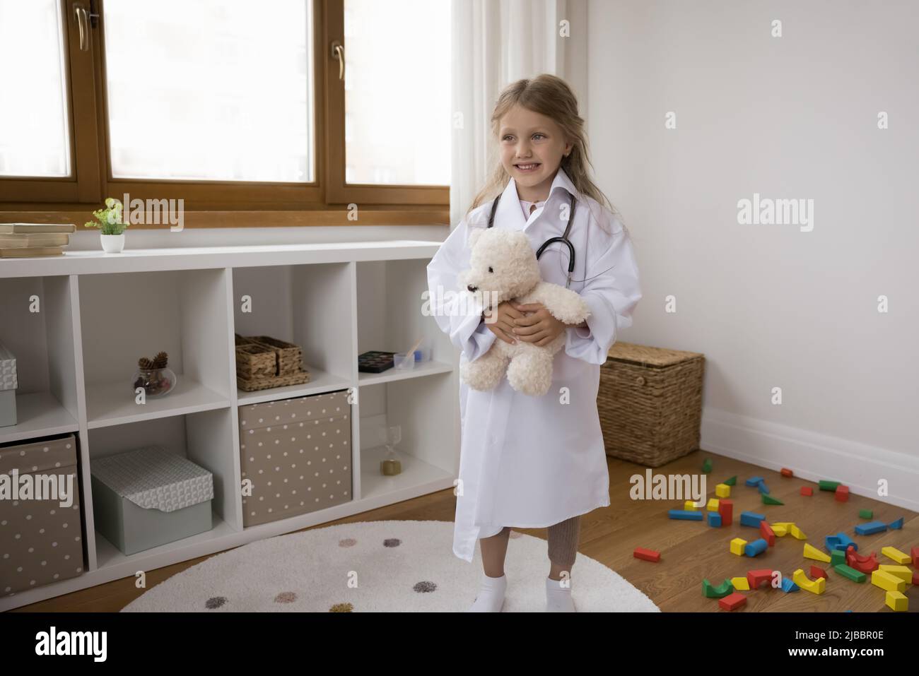 Bambina in cappotto e stetoscopio in posa con giocattolo soffice Foto Stock