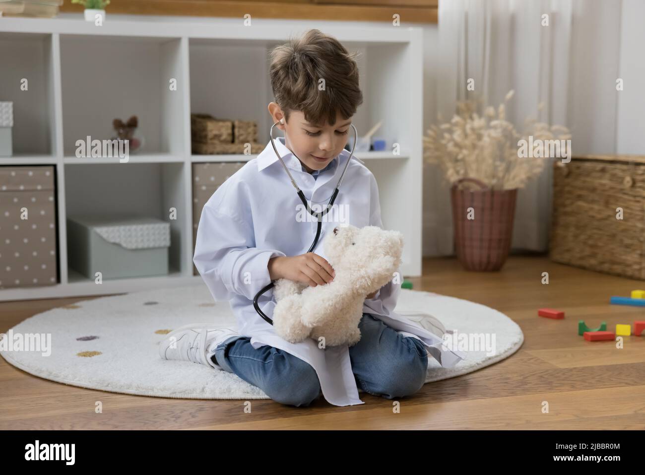 Carino ragazzo in bianco cappotto medico giocando veterinario medico Foto Stock