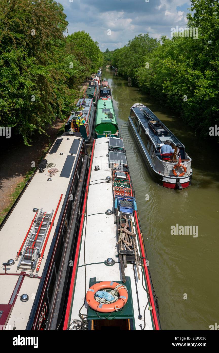 Guardando verso il basso su un battello narrowboat passando un gran numero di barche ormeggiate sul Canal Grand Union vicino a Crick nel Northamptonshire. Foto Stock