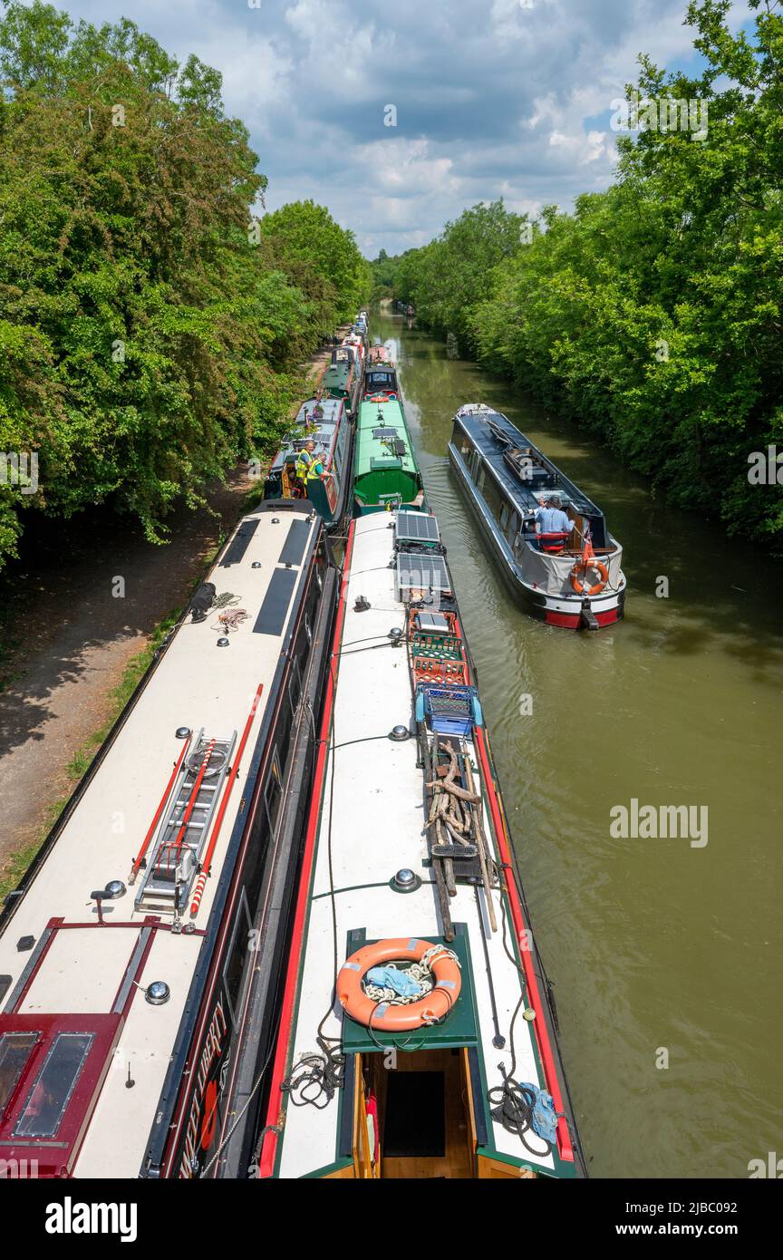 Guardando verso il basso su un battello narrowboat passando un gran numero di barche ormeggiate sul Canal Grand Union vicino a Crick nel Northamptonshire. Foto Stock