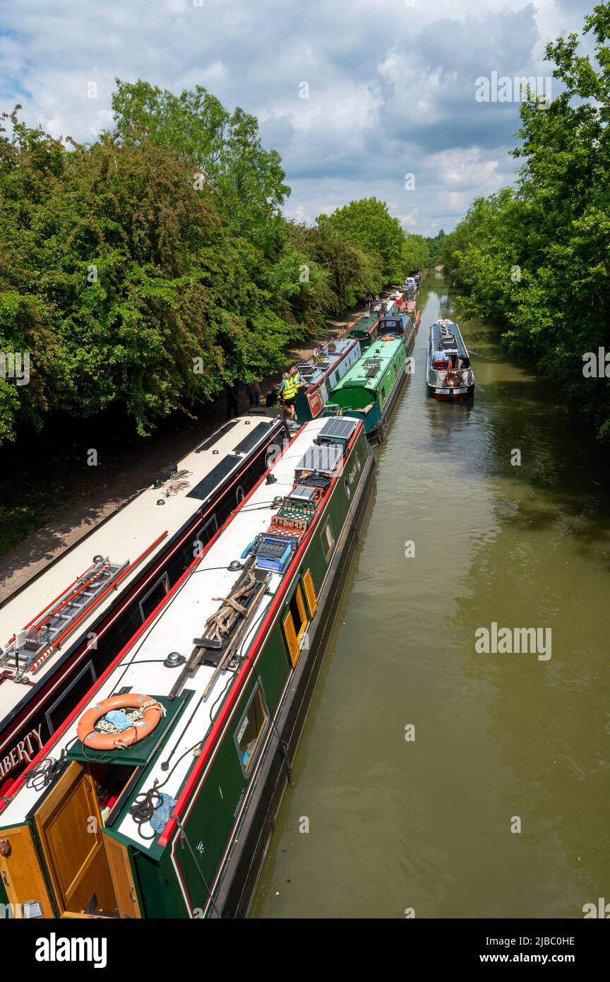 Guardando verso il basso su un battello narrowboat passando un gran numero di barche ormeggiate sul Canal Grand Union vicino a Crick nel Northamptonshire. Foto Stock