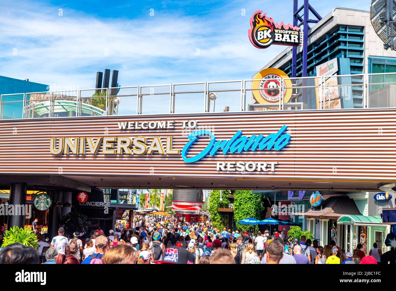 Folla di persone sotto un passaggio pedonale dove si può leggere il cartello Benvenuti all'Universal Orlando Resort.Universal Studios Florida è un luogo famoso Foto Stock