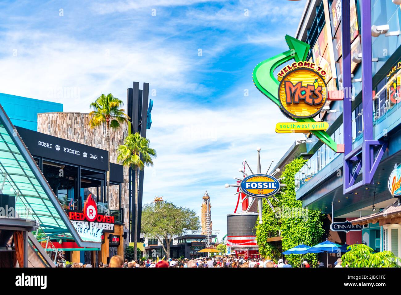 Folla di persone che camminano business insegne che includono Moe's Southwest Grill e Fossil Automatic watches.Universal Studios Florida è un luogo famoso AN Foto Stock