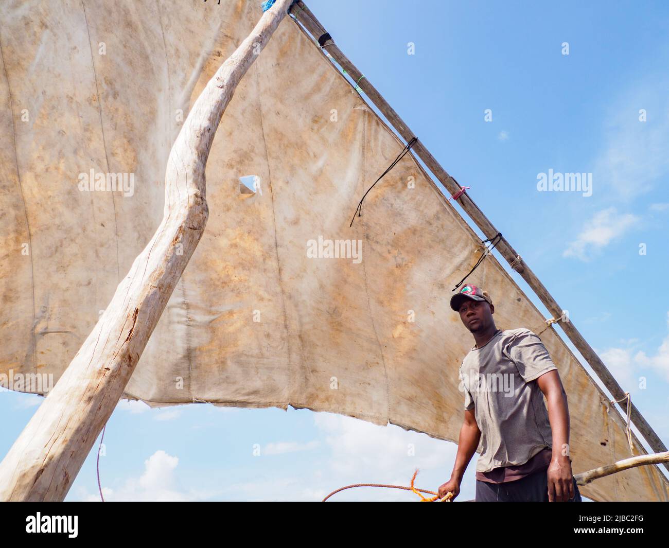 Zanzibar, Tanzania - Gennaio 2021: Giovane pescatore africano che salpa su una barca a vela tradizionale dhow Foto Stock