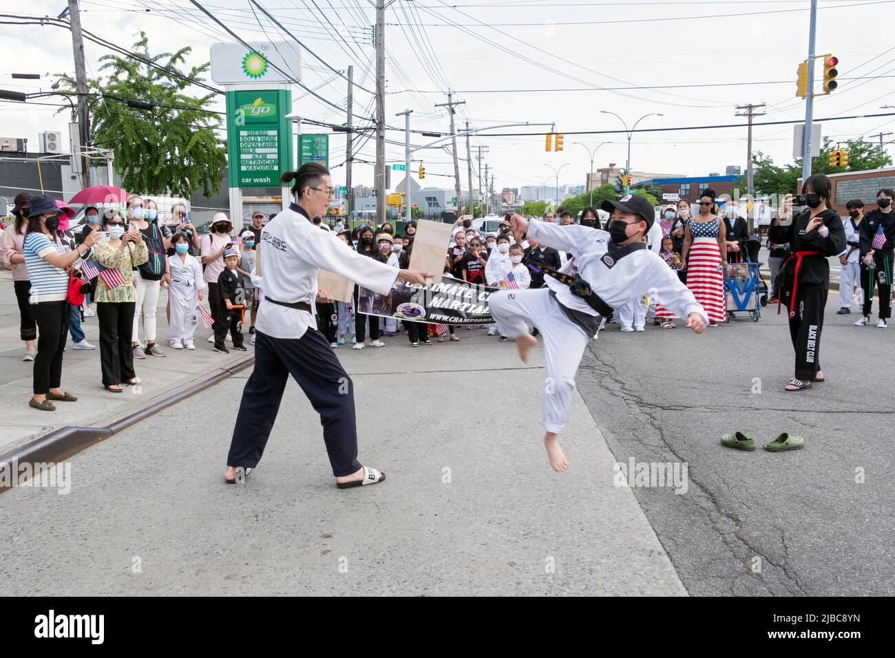 Un ragazzo del campione arti marziali con una cintura nera che calcia un orso di legno. All'inizio della Memorial Day Parade a College Point, Queens, New York. Foto Stock