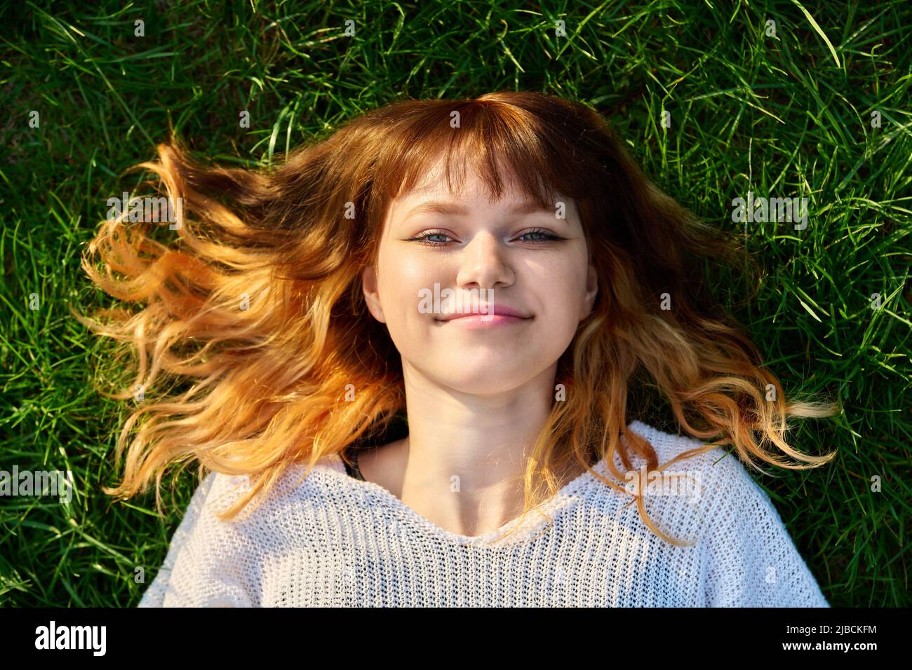 Primo piano volto di felice redhead teenage femmina su sfondo erboso, vista dall'alto Foto Stock