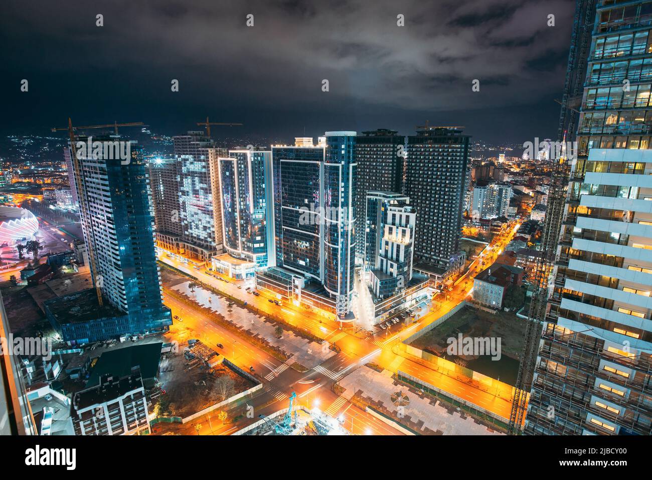 Traffico cittadino di notte di strada e case alte. Panorama sopraelevato skyline cittadino. Illuminazione notturna. Concetto industriale. Edilizia. Foto Stock