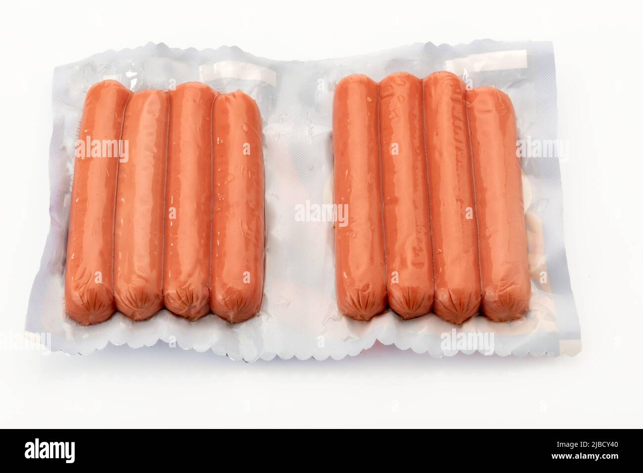 Salsiccia per hot dog o wurstel in confezione sottovuoto sigillato per la cottura sous vide isolato su sfondo bianco in vista dall'alto. Foto Stock