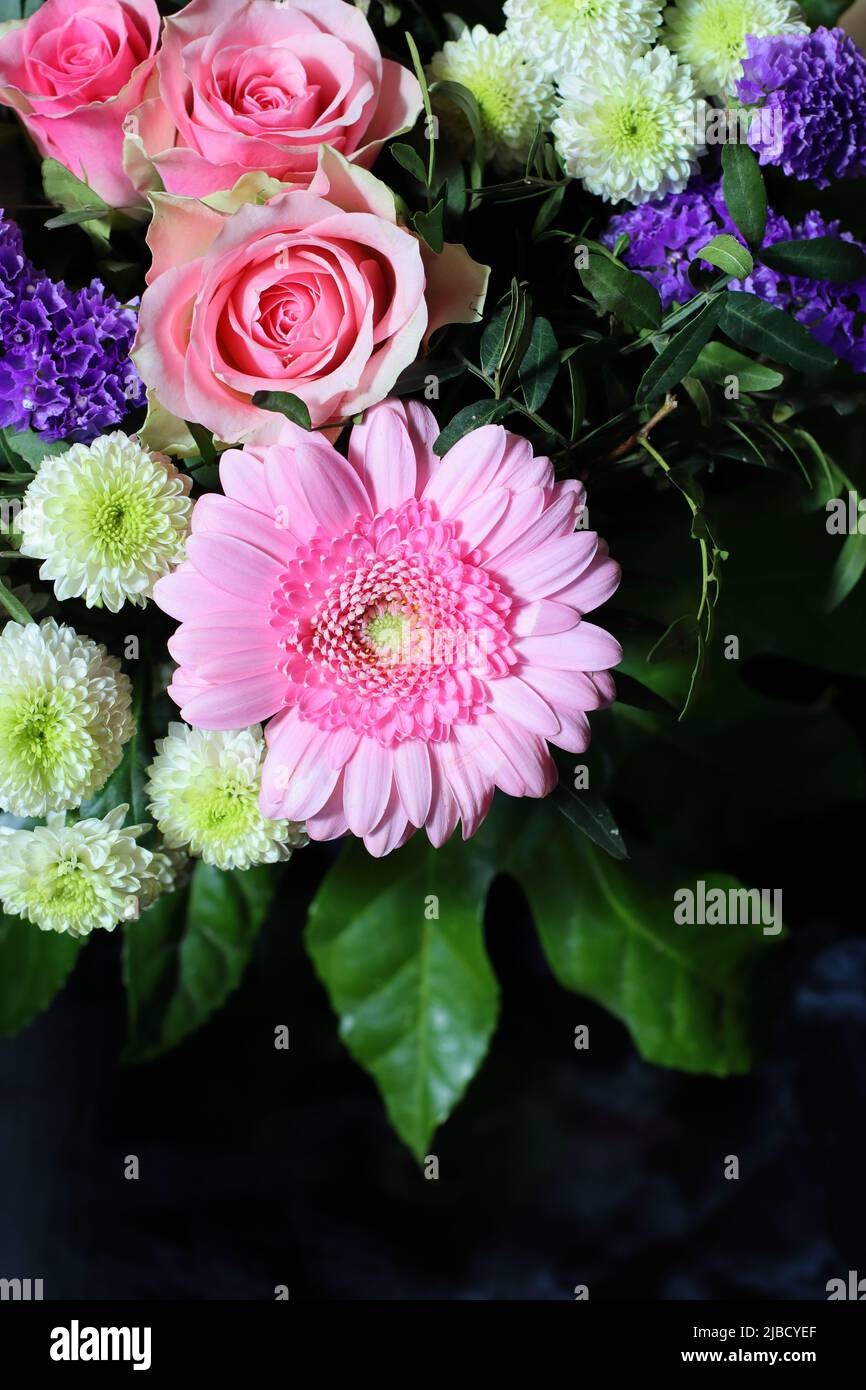 un bel bouquet di fiori con rose rosa e un gerbera rosa chiaro su sfondo scuro, spazio copia, vista dall'alto Foto Stock