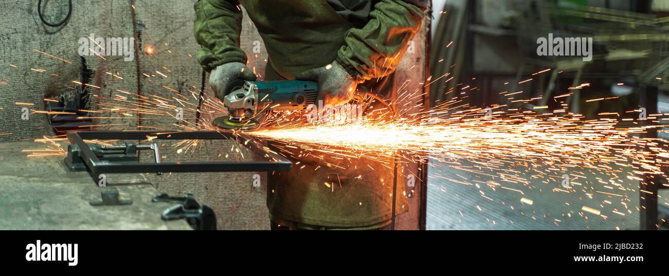 Produzione di fabbri. Lavorazione del metallo con smerigliatrice angolare. Scintille nella lavorazione dei metalli. Foto Stock