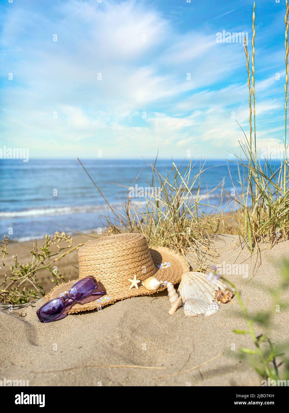 Concetto di estate di spiaggia sabbiosa, cappello di paglia, conchiglie e stelle marine. Foto Stock