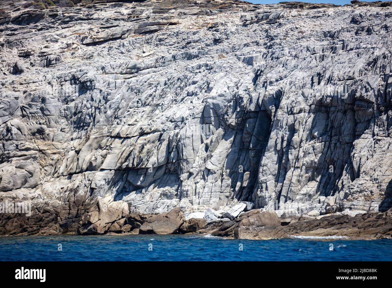 Mar Egeo. Formazioni rocciose, scogliere e grotte, acqua dell'oceano increspata. CICLADI Grecia. Seascape vicino all'isola di Mykonos, giorno di sole Foto Stock