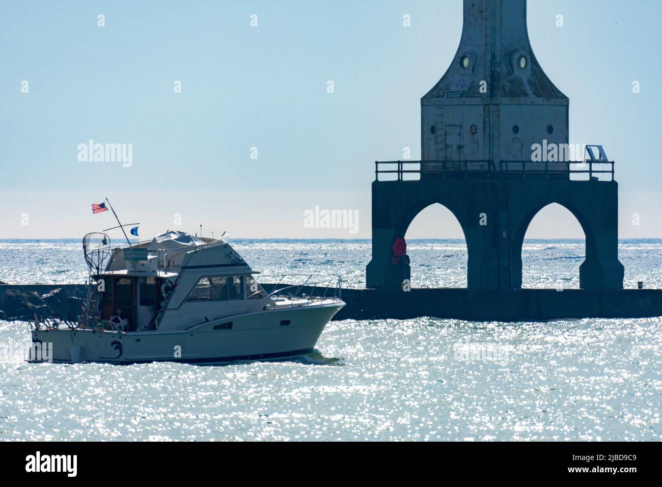 Una barca non identificata passa vicino al Port Washington Break Water Light a Port Washington, Wisconsin, in una mattinata estiva. Foto Stock