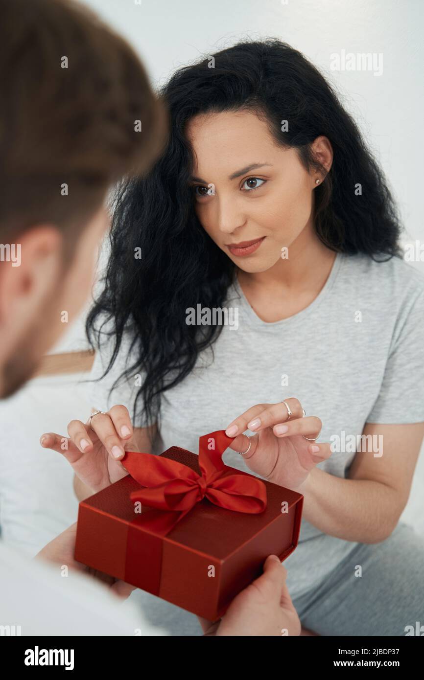 Giovane donna che apre il dono della persona amata Foto Stock