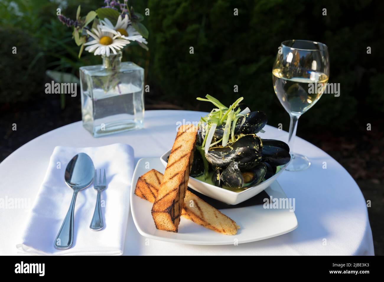 Un piatto di cozze con vino all'aperto Foto Stock