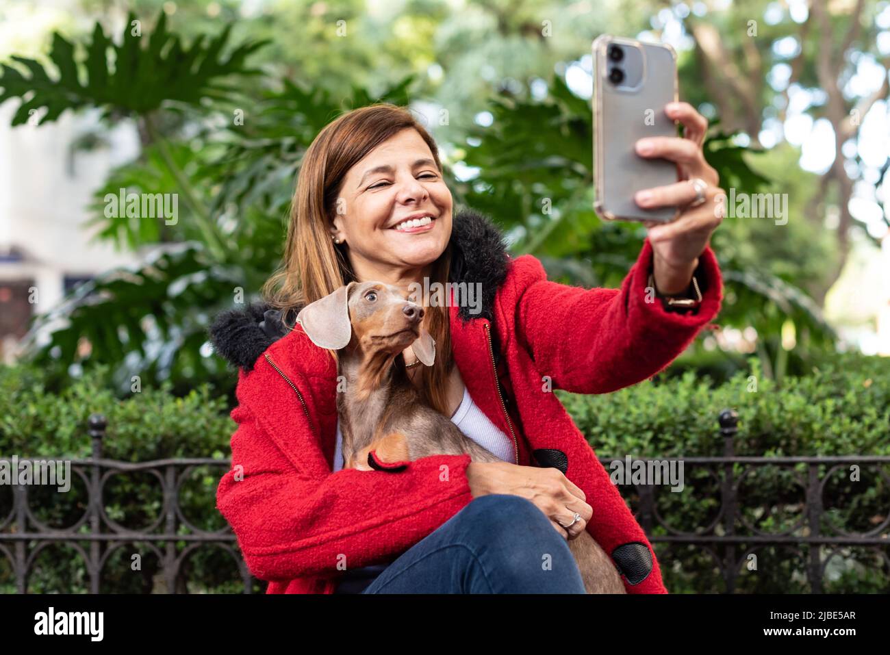 Donna latina che tiene il suo cane mentre prende un selfie di entrambi Foto Stock