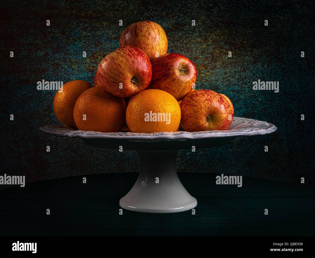 Piatto di frutta, mele e arance. In una foto di Moody, un'immagine di una vita morta, mele fresche e arance. Suggerimento per l'uso su un canvas. Foto Stock