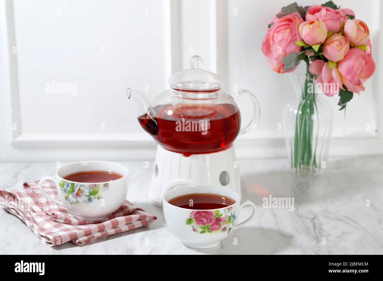 Tazza da tè Flowery con teiera in vetro trasparente su sfondo bianco, tè inglese concetto tempo Foto Stock