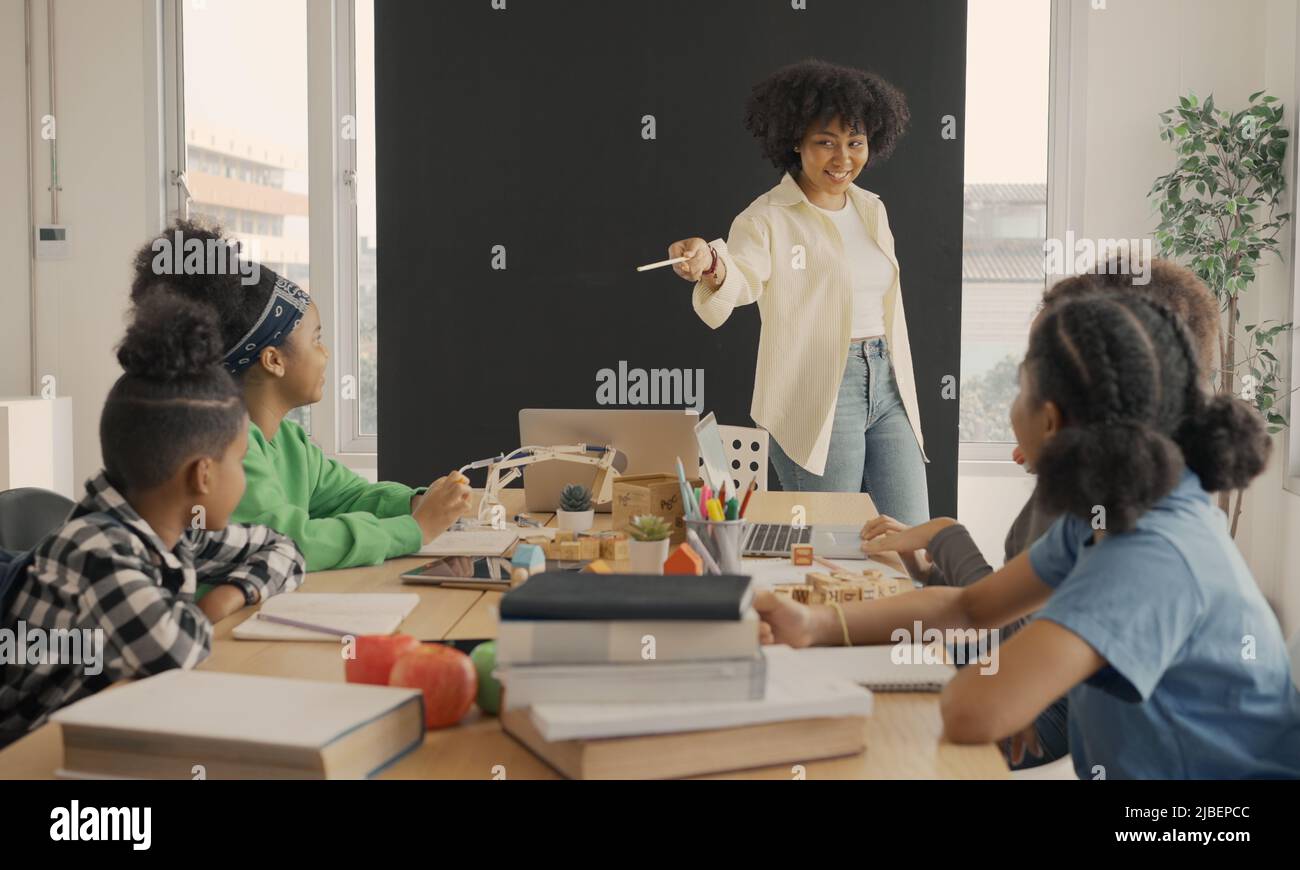 Classe con diversi studenti di studenti felicemente afroamericani e insegnanti che svolgono attività insieme. L'insegnante sta insegnando, guidando e talki Foto Stock