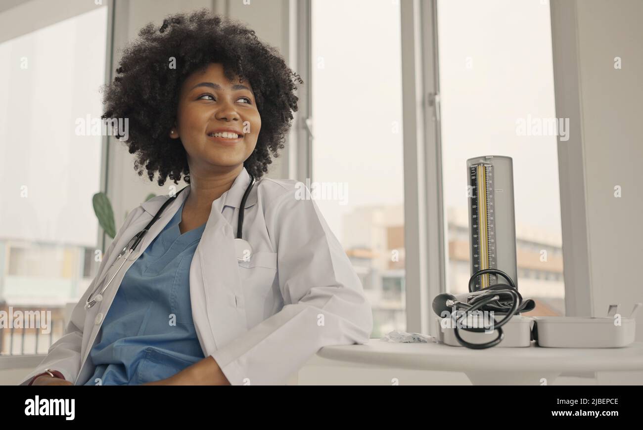 Ritratto di una donna sorridente medico che indossa un cappotto bianco con uno stetoscopio in un ufficio ospedaliero. Foto Stock