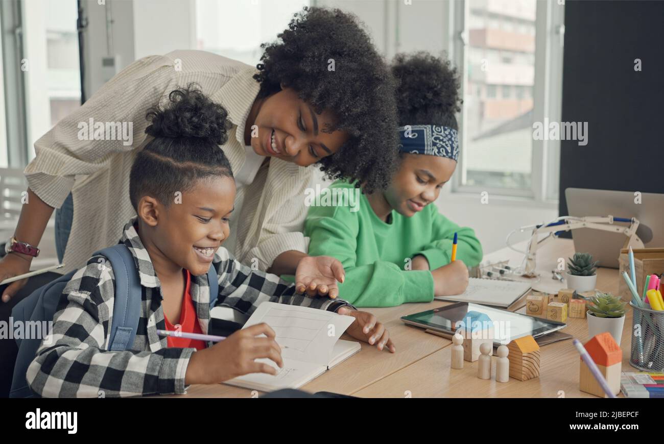 Classe con diversi studenti di studenti felicemente afroamericani e insegnanti che svolgono attività insieme. L'insegnante sta insegnando, guidando e talki Foto Stock
