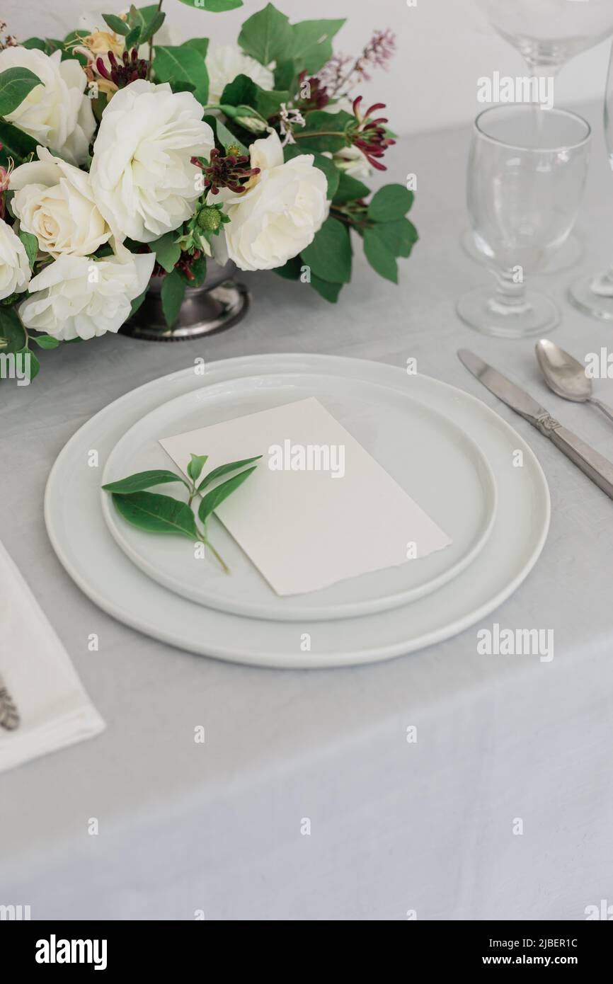 Una bella rosa bianca floreale disposizione su un tavolo da pranzo con candele su iit. Tavolozza grigia e bianca. Sito web o workshop di progettazione di matrimoni. Foto Stock
