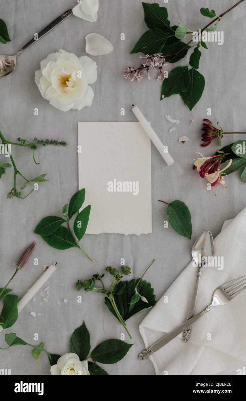 Una bella rosa bianca floreale disposizione su un tavolo da pranzo con candele su iit. Tavolozza grigia e bianca. Sito web o workshop di progettazione di matrimoni. Foto Stock