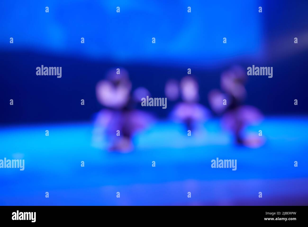 Sfondo sfocato di un festival di danza da un gruppo di bambine. Illuminazione luminosa del palco blu della pista da ballo. Foto di alta qualità Foto Stock