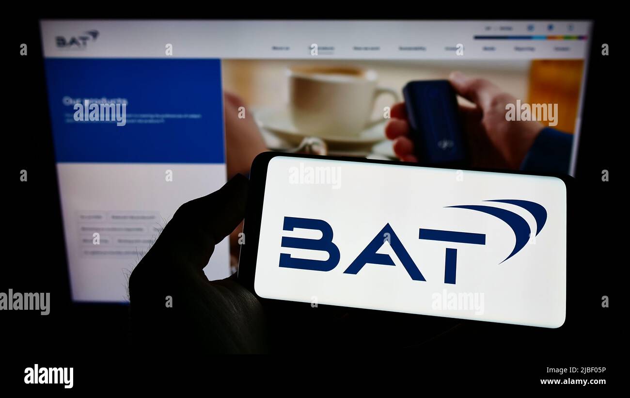 Persona che tiene smartphone con il logo della società British American Tobacco plc (BAT) sullo schermo di fronte al sito web. Mettere a fuoco sul display del telefono. Foto Stock