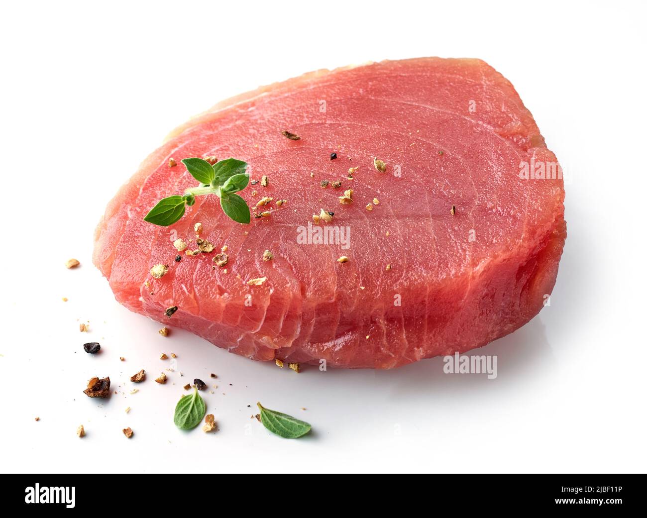 bistecca di tonno fresco crudo con erbe e spezie isolate su sfondo bianco Foto Stock
